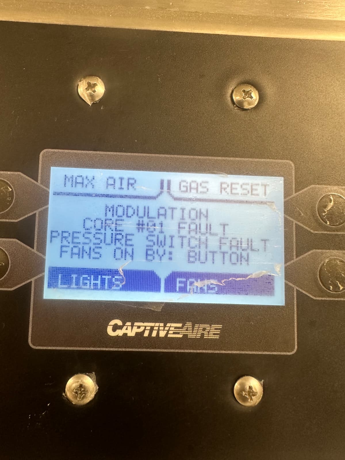 CaptiveAire releasing control panel display showing TEST MODE with the discharge output armed and a confirmation prompt before firing — yellow trouble LED active, alarm output disabled, technician's hand near the soft-key array