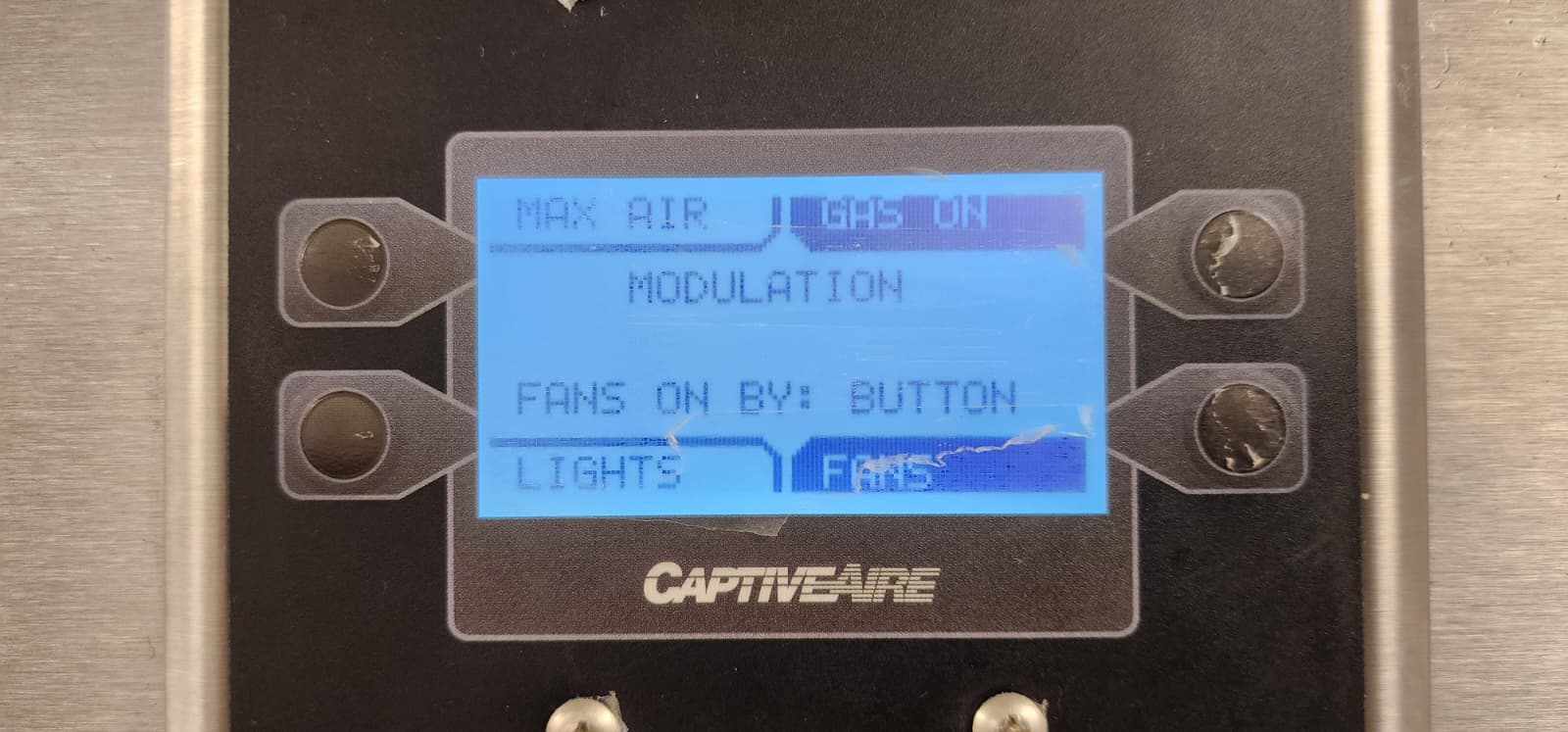 CaptiveAire LDC hood control panel showing a backlit LCD with status text reading MAX AIR / GAS ON / MODULATION / FANS ON BY: BUTTON / LIGHTS / FANS, with four soft-key membrane buttons surrounding the display and the CaptiveAire logo below