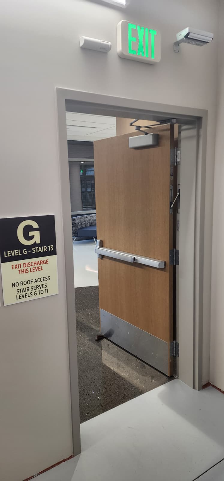 Rated fire corridor doors held open by a wedge, defeating fire and smoke compartmentalization