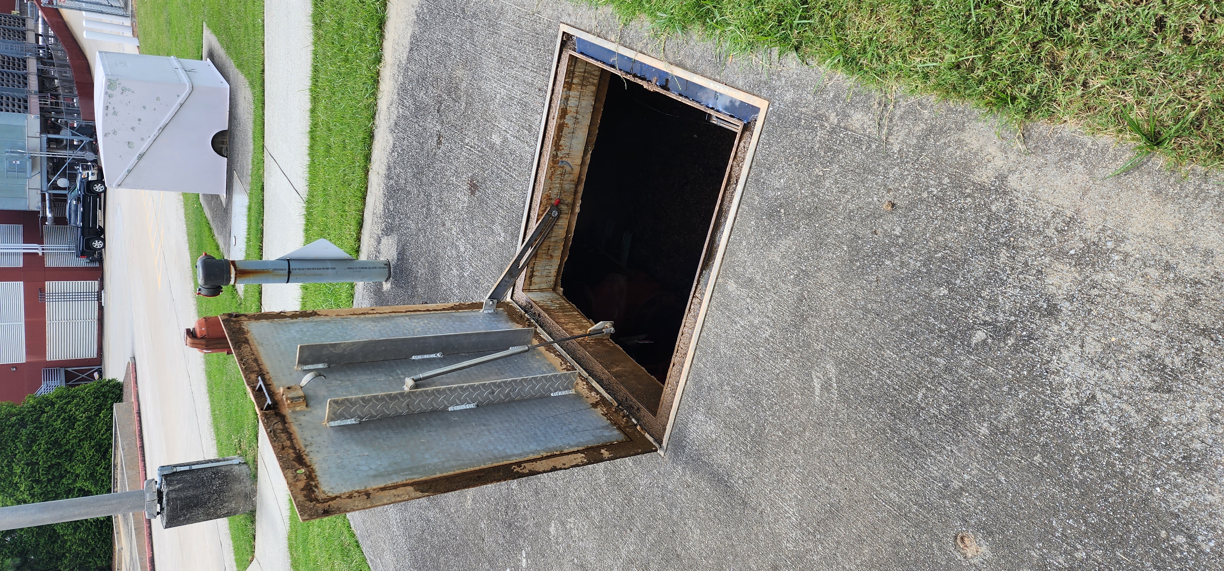 Open hatch on a below-grade backflow preventer vault showing the assembly and drainage