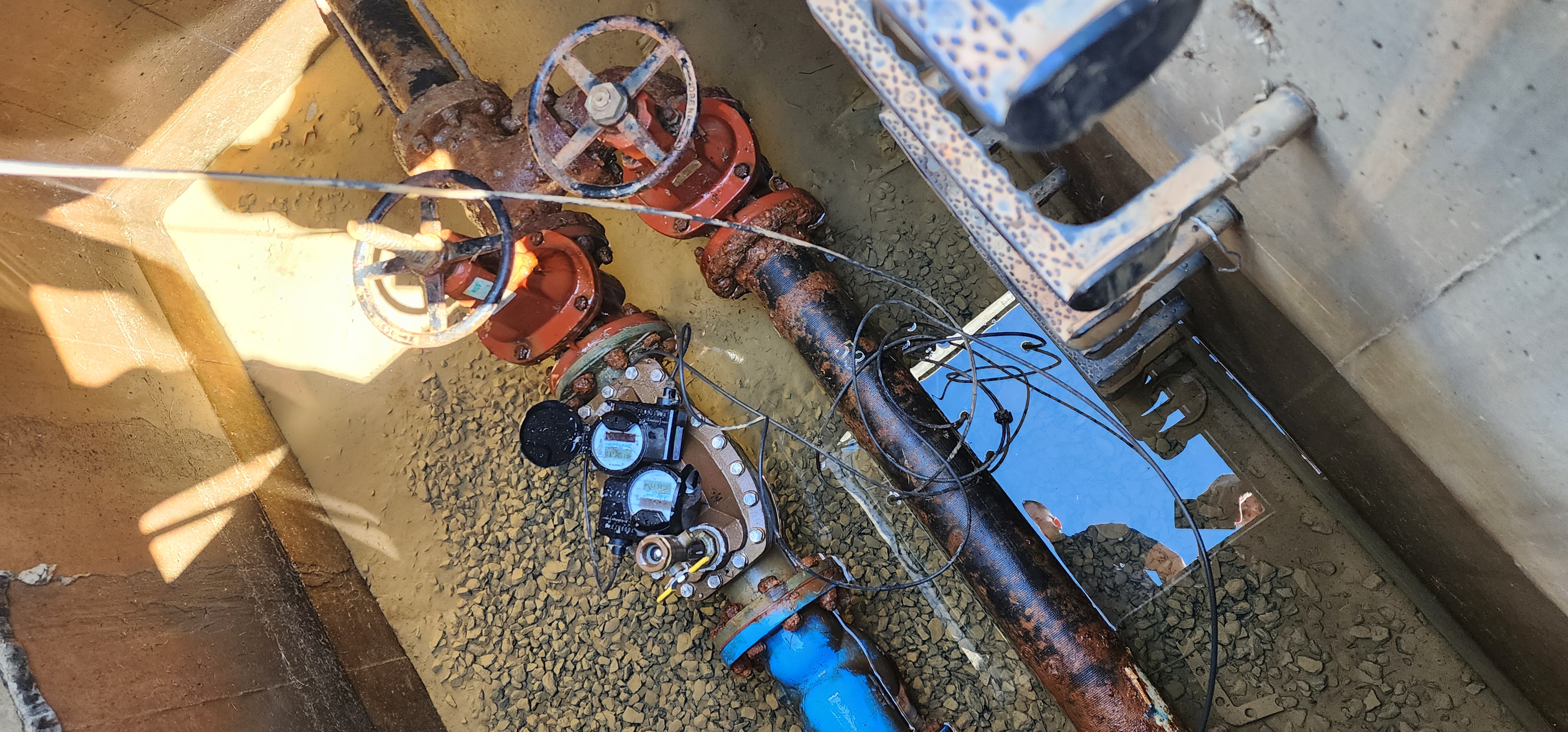 AMR water meter inside a below-grade utility vault, showing brass service piping and an encoder register