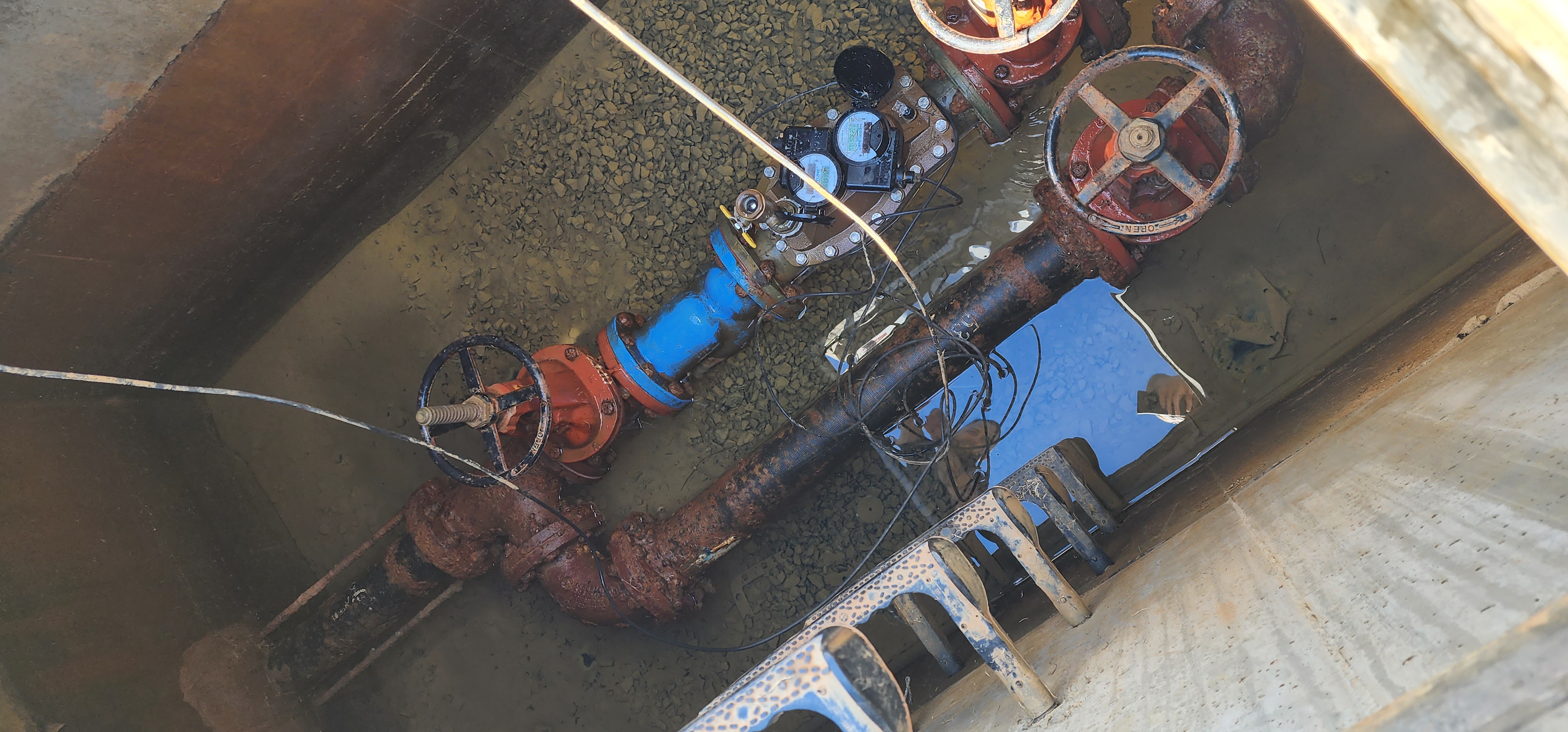 Overhead view of a water-service vault with the AMR meter visible through the open hatch