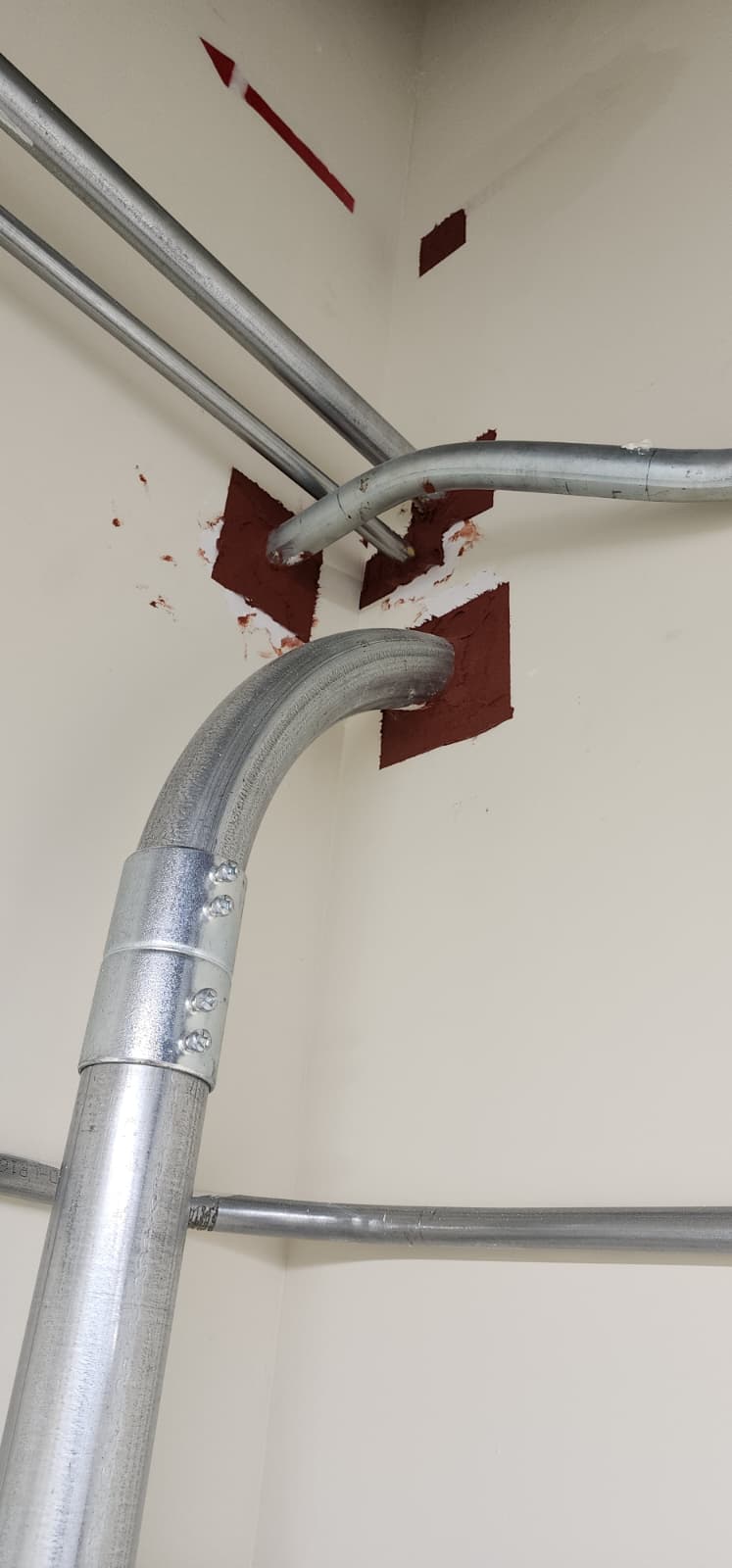 Wall penetration with multiple conduits sealed with red intumescent firestop