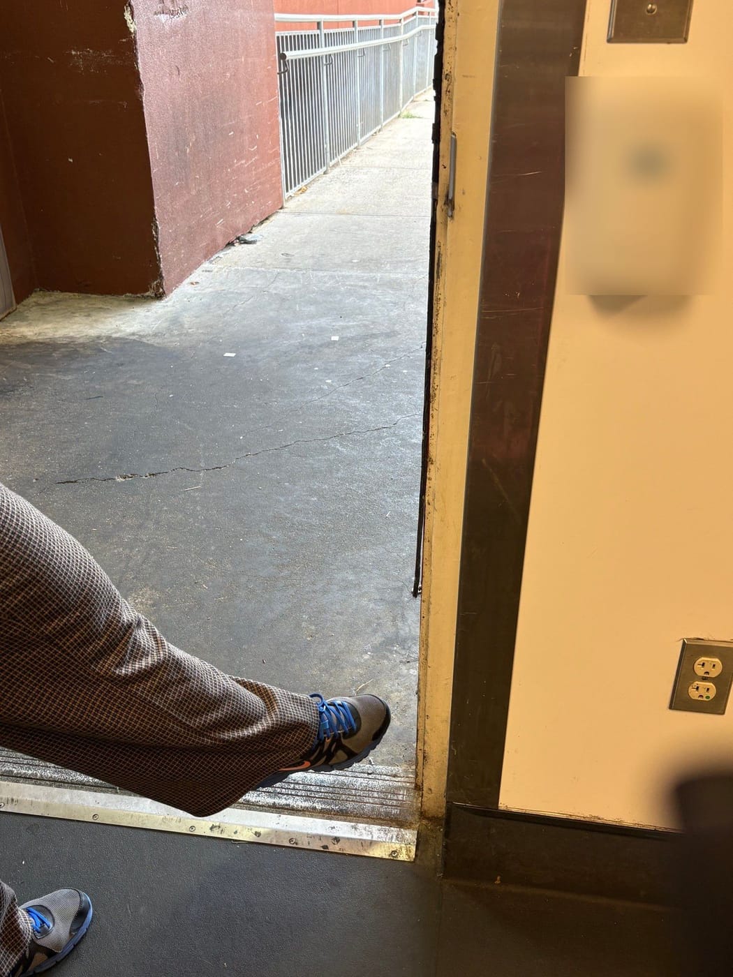 An open exterior door frame with a torn, damaged smoke seal along its edge