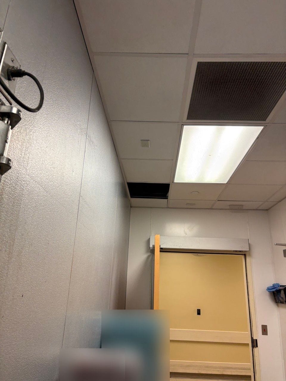A kitchen storage room ceiling with one ceiling tile missing near the wall