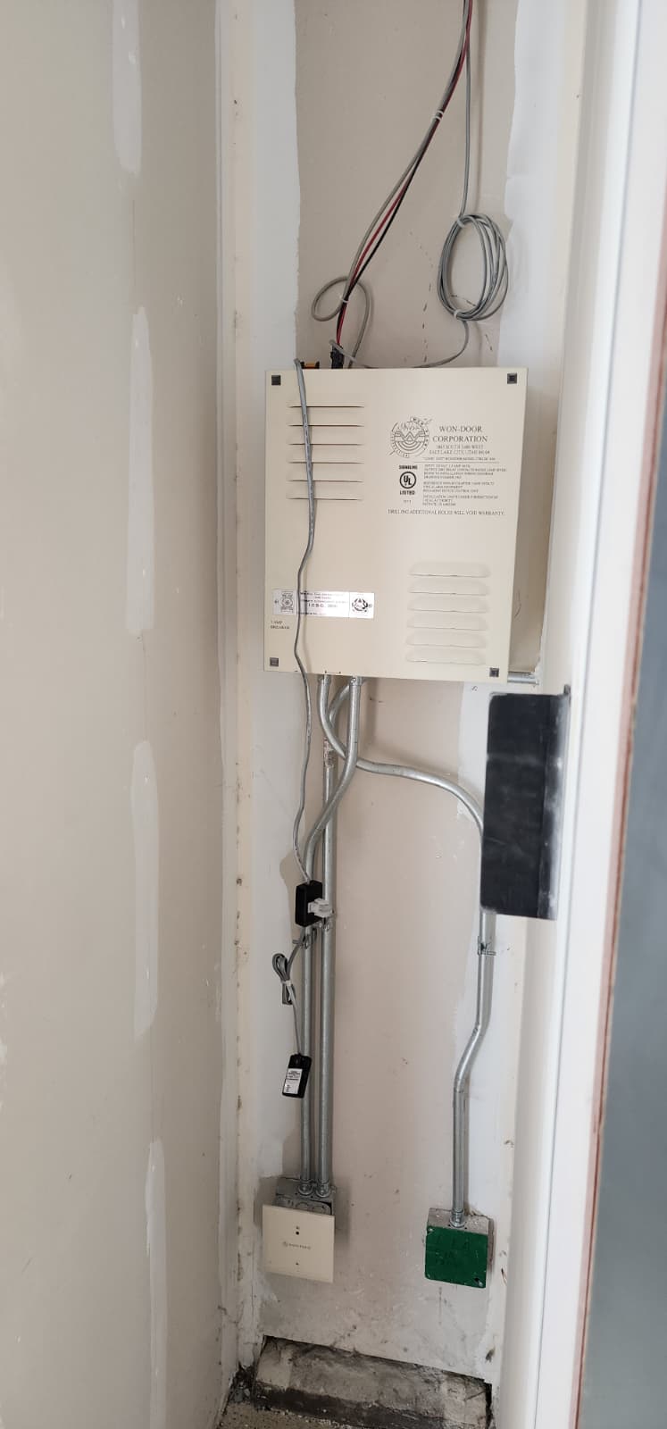 Close-up of a WON-Door Corporation controller enclosure showing the UL Listed label and wiring harness connections at the bottom