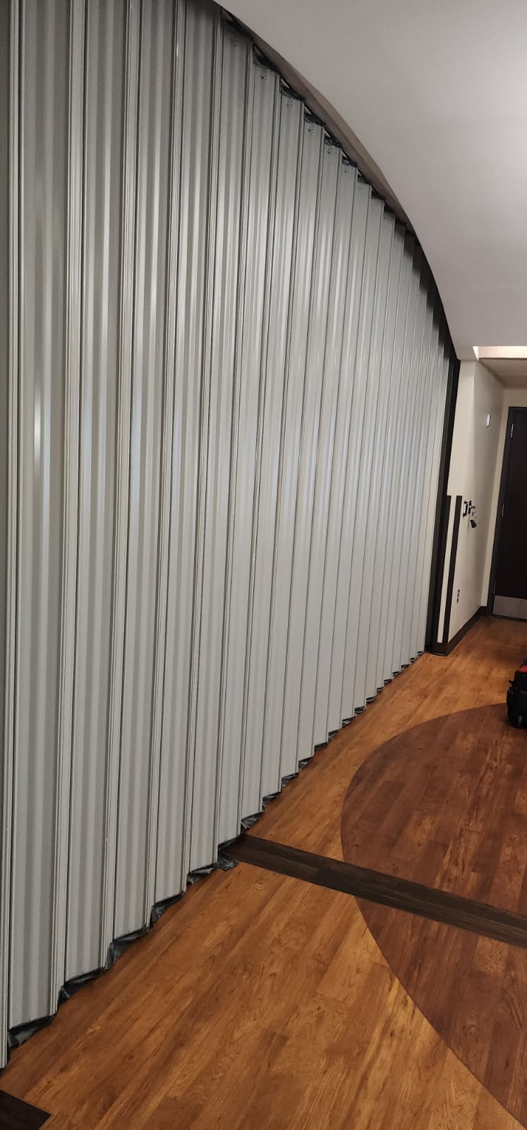Wide WON-Door accordion fire door in the closed position following a curved corridor path, with the overhead curved track housing visible above