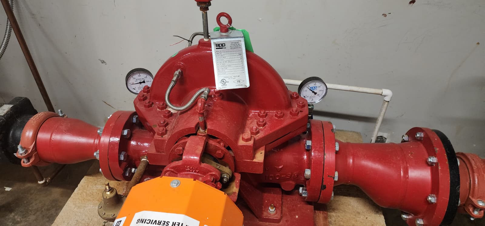 Top view of an SPP horizontal split-case fire pump with UL Listed/FM Approved nameplate, two SPP pressure gauges, stainless flex hose connecting the gauges to the volute, grooved couplings on suction and discharge, and visible coupling guard