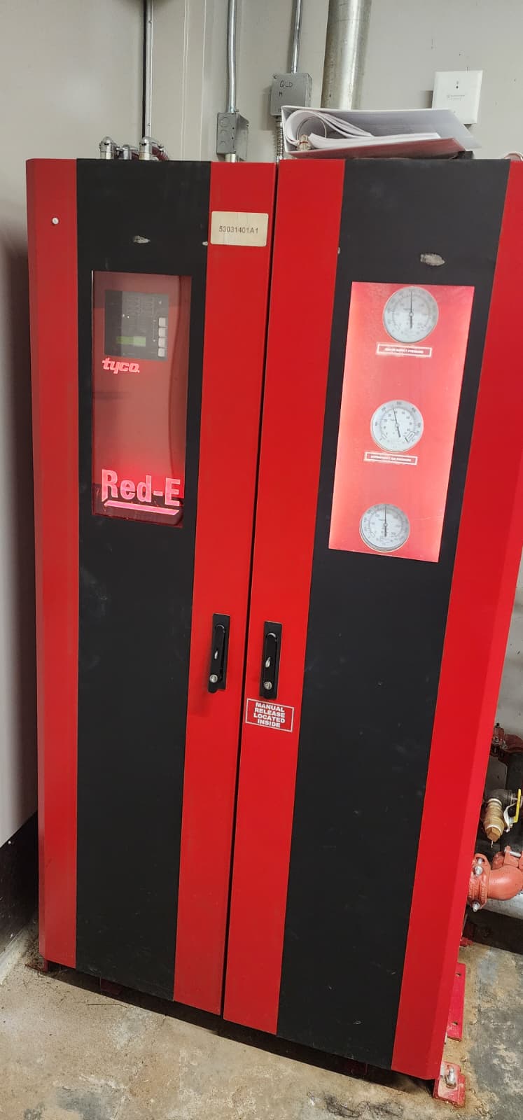 Tyco Red-E fire pump controller cabinet with two doors — left side has the digital display and manual release label, right side has three pressure gauges (suction, discharge, sensing line)