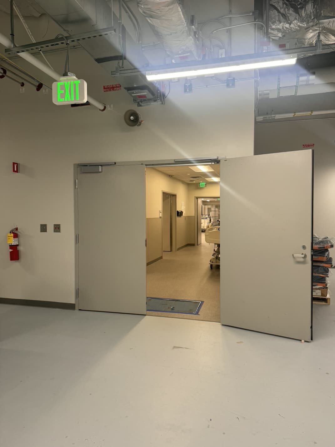 A corridor fire door held open with a wooden wedge